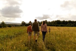 Family walking into a grassy meadow with their backs towards the camera